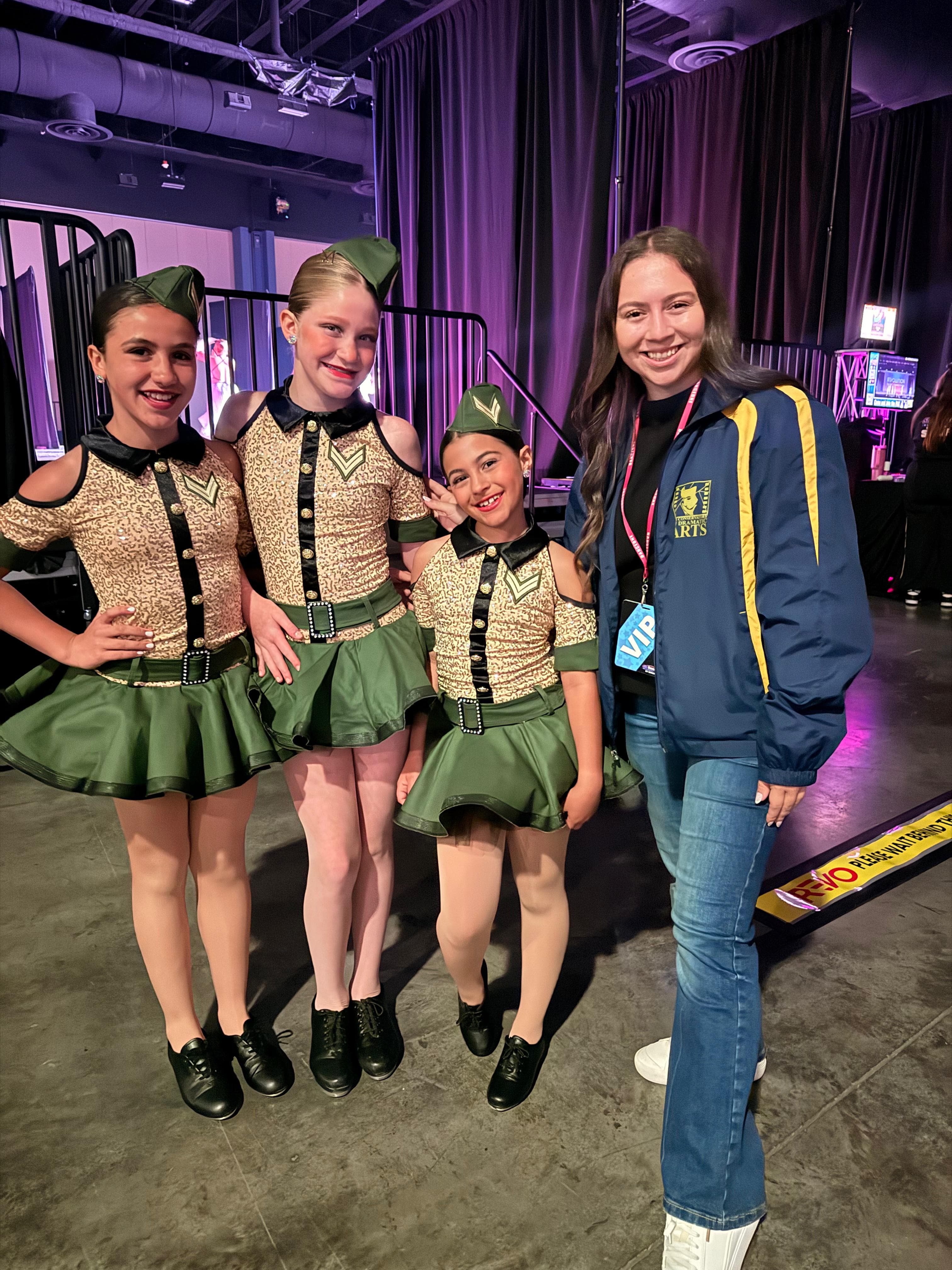 Estudiantes de Piojos con vestuario de baile sonriendo tras bambalinas